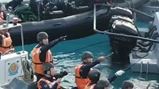 Chinese Coast Guard hold knives and machetes as they approach Philippine troops on a resupply mission in the Second Thomas Shoal