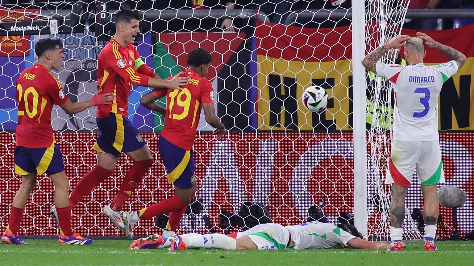 Spanyol játékosok (pirosban) örülnek az olasz Riccardo Calafiori (a földön) öngóljának a spanyol - olasz Eb-mérkőzésen a gelsenkircheni AufSchalke Arénában 2024. 06.20-án.