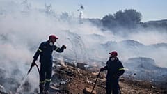 Feuerwehrleute versuchen, das Feuer zu löschen, während ein Hubschrauber am 19. Juni 2024 im Vorort Koropi im Osten Athens Wasser abwirft.