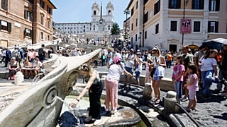 يصطف الناس عند النافورة لإنعاش أنفسهم في يوم حار في ساحة Piazza di Spagna في روما
