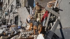 Ein Rettungshelfer mit einem Hund sucht nach Opfern in einem beschädigten Wohnhaus nach einem russischen Bombeneinschlag in Charkiw, Ukraine, Samstag, 22. Juni 2024. 