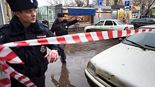Полицейские устанавливают ленту на месте преступления возле подозрительного автомобиля (на заднем плане) в Москве, Россия, суббота, 28 февраля 2015 года. 