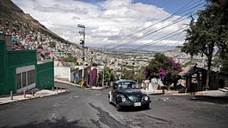 A 1996 Volkswagen Beetle is drivn up a steep hill in the Cuautepec neighborhood of Mexico City