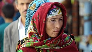 A woman in traditional colorful Tajik dress carries a bundle of bread at the Green Bazaar, in Dushanbe, 7 October 2001