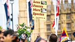 A protestor holds a placard reading 'Less faeces, more species' at the Restore Nature Now rally in London, June 2024.