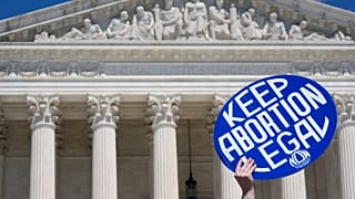 A person holds up a sign as abortion rights activists and Women's March leaders protest as part of a national day of strike actions outside the Supreme Court