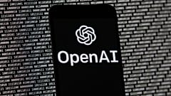 El logotipo de OpenAI aparece en un teléfono móvil frente a una pantalla de ordenador con datos binarios aleatorios, el jueves 9 de marzo de 2023, en Boston. 