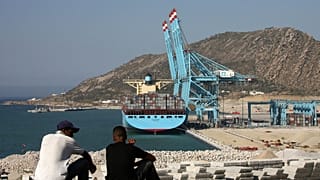 عاملان مغربيان ينظران إلى ميناء طنجة ​​بعد افتتاحه من قبل الملك المغربي محمد السادس في مدينة طنجة الشمالية، الجمعة 27 يوليو 2007
