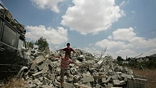 فتية فلسطينيون يقفون على أنقاض منزل هدمه الجيش الإسرائيلي في قرية اللبن الغربية بالضفة الغربية، بالقرب من رام الله.