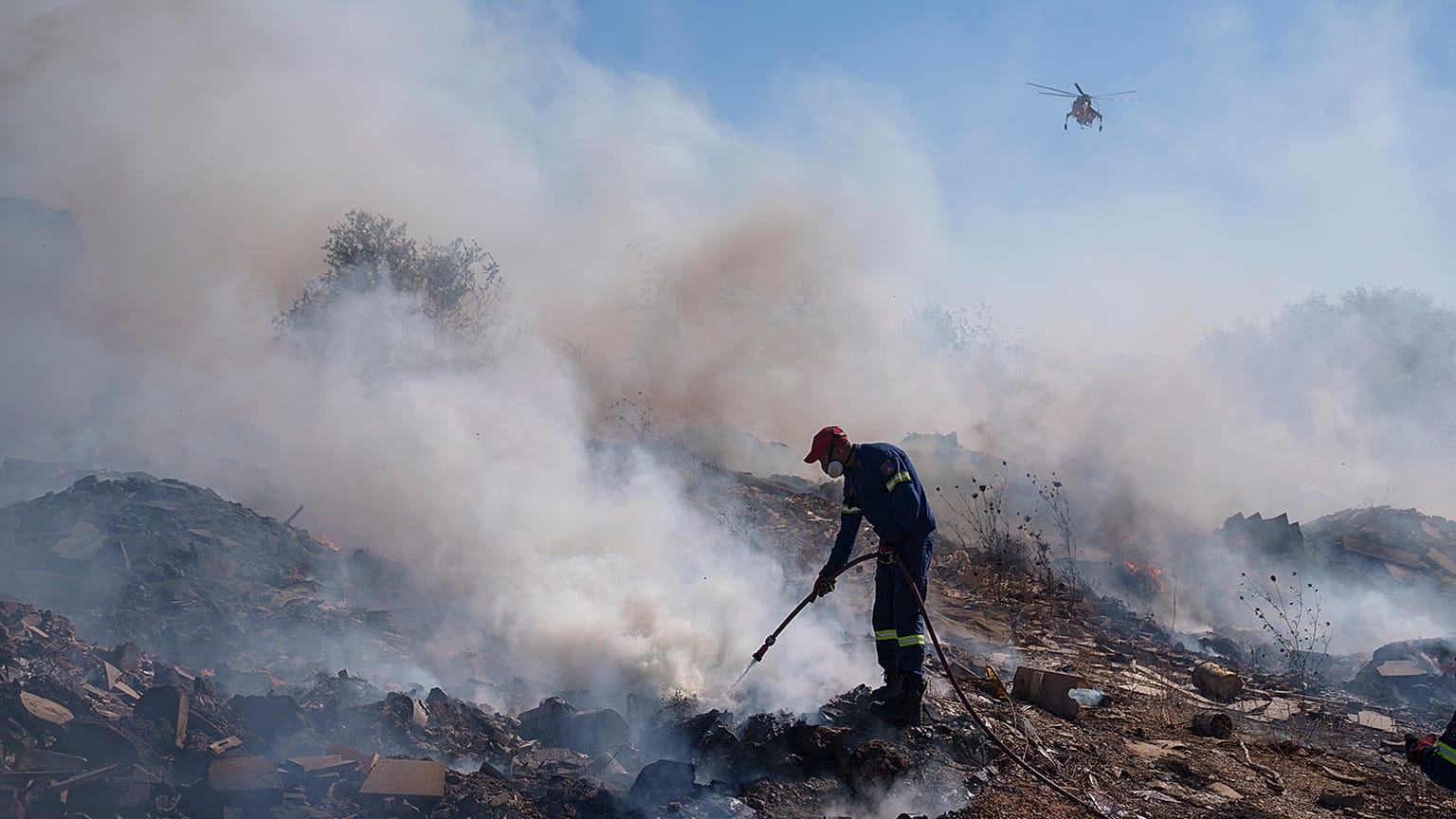 A firefighter tries to extinguish a fire burning in Koropi suburb, eastern part of Athens, 19 June 2024