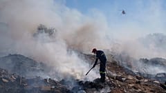 A firefighter tries to extinguish a fire burning in Koropi suburb, eastern part of Athens, 19 June 2024