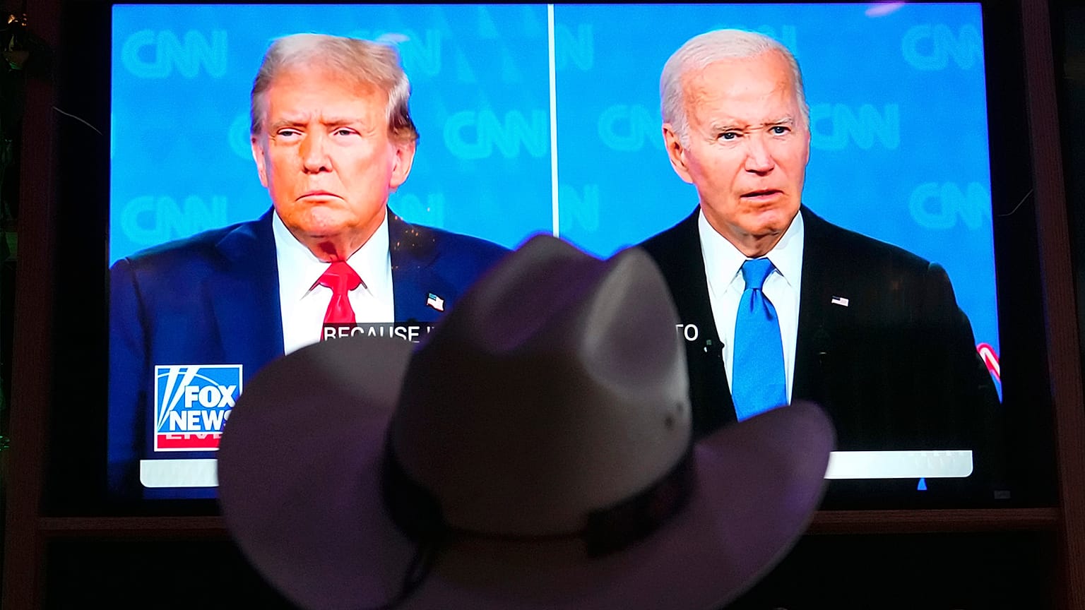 A man wears a cowboy hat as he watches the presidential debate between Joe Biden and Donald Trump in Scottsdale, AZ, 27 June 2024