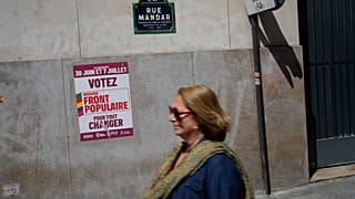 Μια γυναίκα περπατά μπροστά από μια αφίσα που γράφει "Ψηφίστε το Νέο Λαϊκό Μέτωπο" ενόψει των επερχόμενων βουλευτικών εκλογών στο Παρίσι.