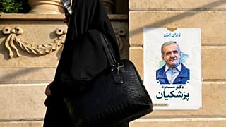 A woman walks past a poster of reformist candidate Masoud Pezeshkian in Tehran, June 29, 2024