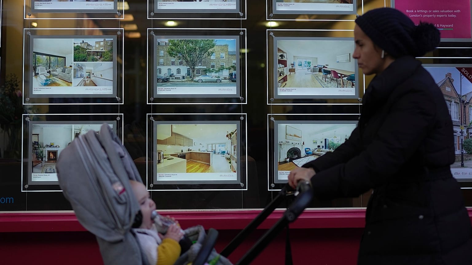 A woman walks past an estate agent in London.