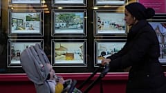 A woman walks past an estate agent in London.