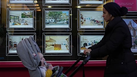 A woman walks past an estate agent in London.