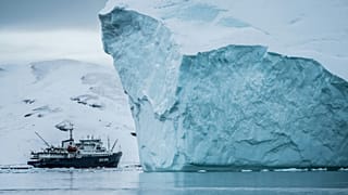 A ship goes past an Iceberg in Arctic waters.