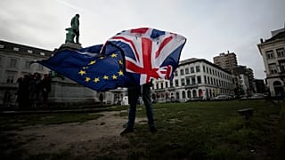 Peter Cook, apoiante pró-UE, desfralda uma bandeira da União e da UE antes de uma cerimónia para celebrar a amizade entre o Reino Unido e a UE, em frente ao Parlamento Europeu, em Bruxelas.