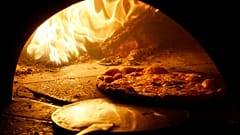 Μια πίτσα με επικάλυψη από μοτσαρέλα ψήνεται σε παραδοσιακό φούρνο με ξύλα στο κέντρο της Νάπολης.