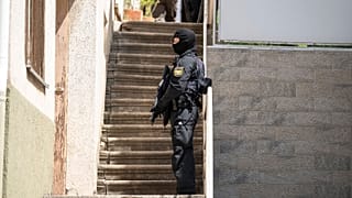 A police officer stands in front of a door with a submachine gun in Althengstett, 4 June 2024