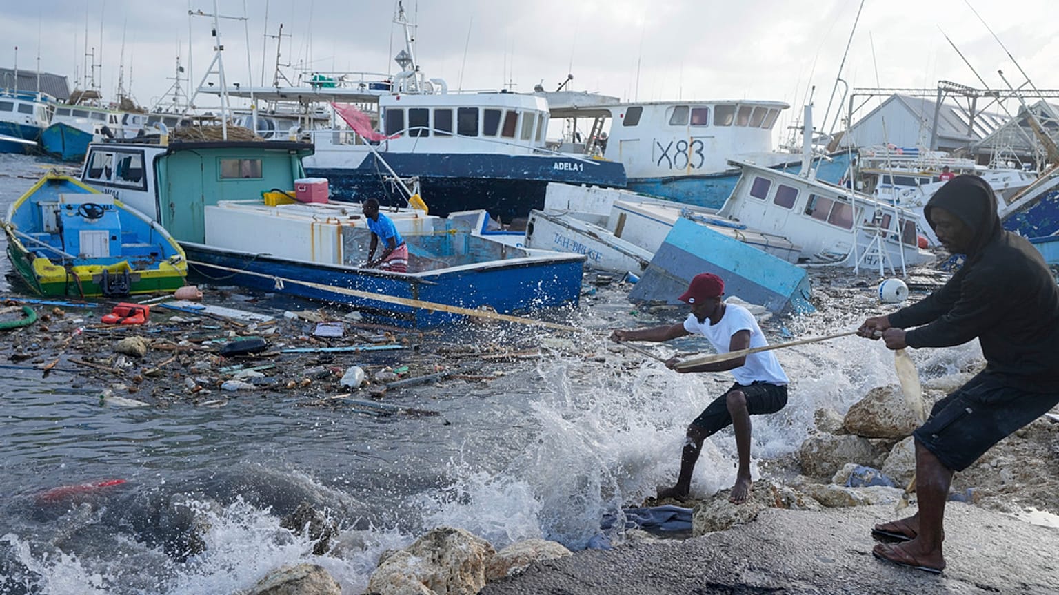 Fishermen pull a boat damaged by Hurricane Beryl back to the dock at the Bridgetown Fisheries in Barbados