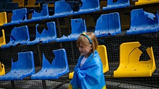 Ein junges Mädchen steht vor den zerstörten Sitzen des Sonyachny-Stadions in Charkiw, das für die Euro 2012 gebaut wurde.