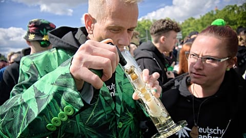 A man smokes as people celebrate at the Brandenburg Gate during a rally and festival to legalise cannabis, in Berlin in April