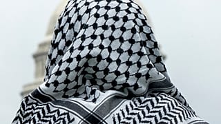 رجل يرتدي الكوفية ينظر إلى مبنى الكابيتول الأمريكي خلال مسيرة مؤيدة للفلسطينيين، في 18 مايو/أيار 2024، في المتنزه الوطني في واشنطن.
