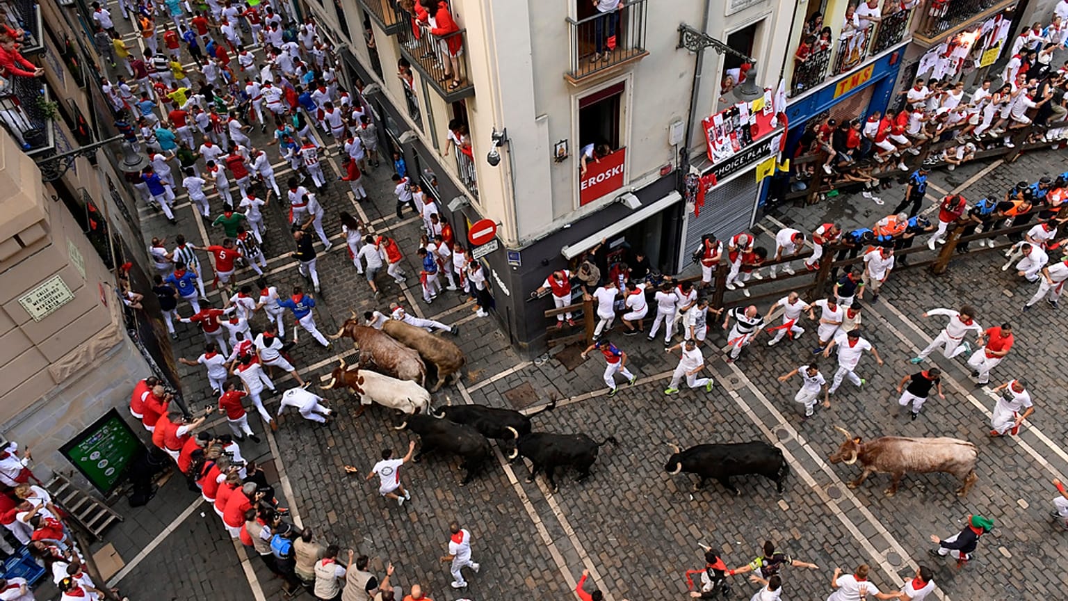 Feiernde rennen mit Stieren von der José Escolar-Ranch am siebten Tag der Stierrennen bei den Sanfermínes in Pamplona, 13. Juli 2024. 