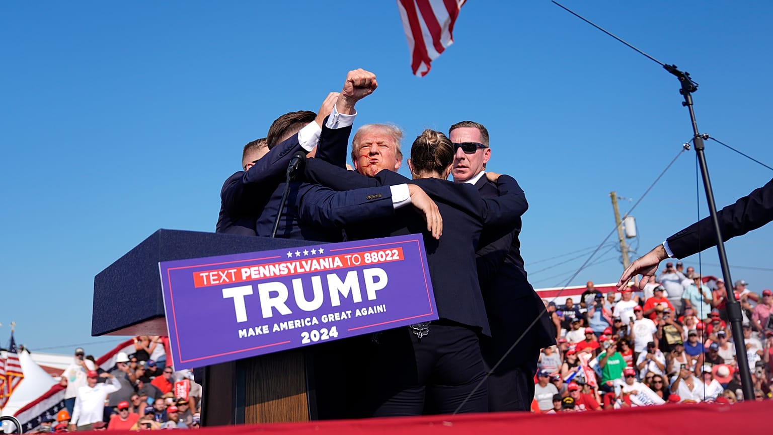 Former President Donald Trump gestures as he is surrounded by Secret Service agents as he leaves the stage in Butler, July 13, 2024