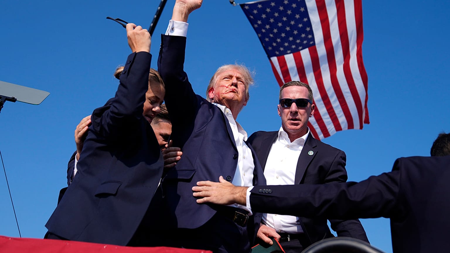 Republican presidential candidate former President Donald Trump gestures as he is surrounded by U.S. Secret Service agents as he leaves the stage at a campaign rally
