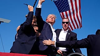 Republican presidential candidate former President Donald Trump gestures as he is surrounded by U.S. Secret Service agents as he leaves the stage at a campaign rally