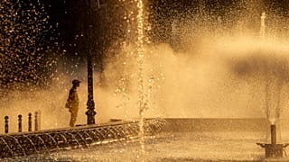 Um trabalhador municipal refresca-se junto a uma fonte da cidade em Bucareste, Roménia, quinta-feira, 11 de julho de 2024, quando as temperaturas ultrapassaram os 39 graus