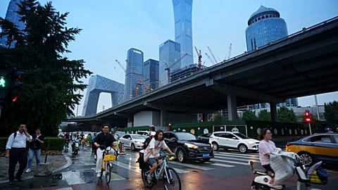 Pedestrians cross an intersection with the background of the central business district in Beijing, July 12 2024 
