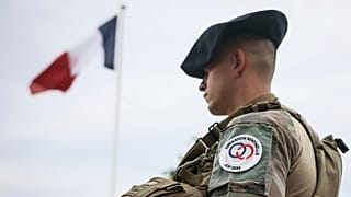 Um soldado junto à bandeira francesa no acampamento militar montado no bosque de Vincennes, segunda-feira, 15 de julho de 2024, nos arredores de Paris.