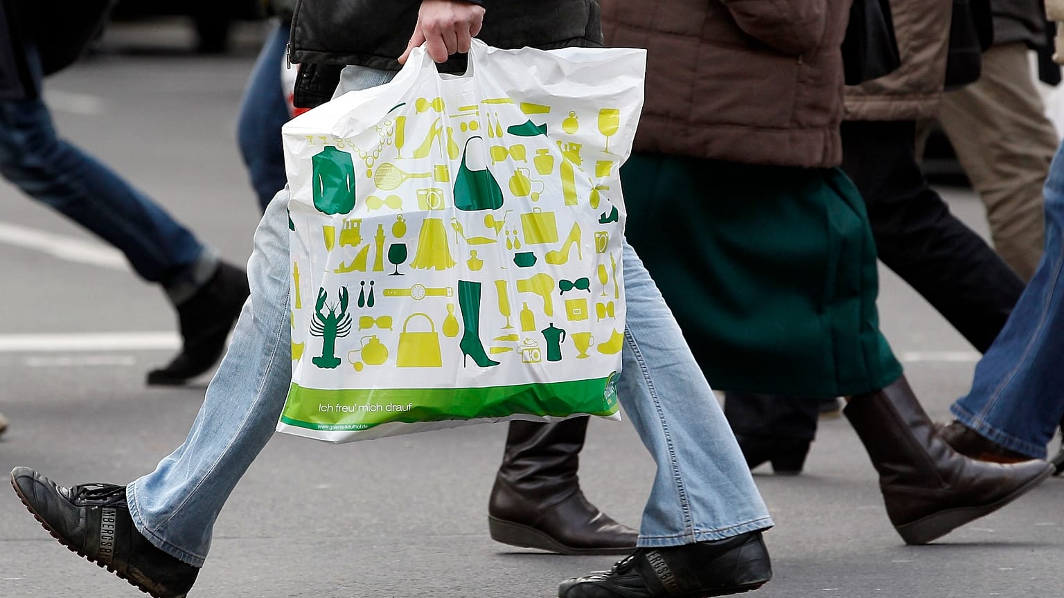 Un uomo con una borsa della spesa attraversa una strada a Berlino, Germania