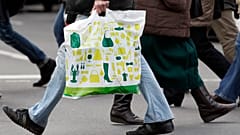 Ein Mann mit einer Einkaufstasche überquert eine Straße in Berlin, Deutschland