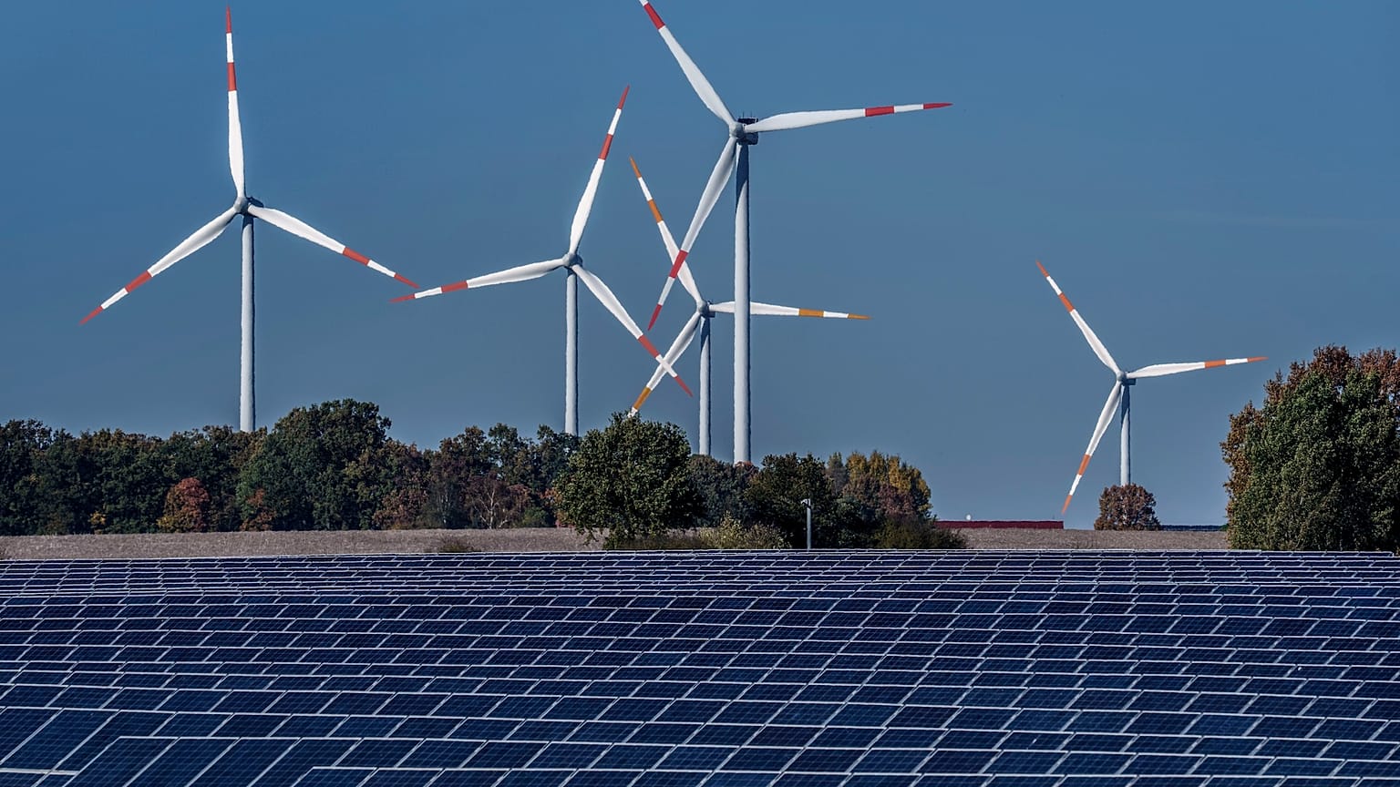 Rüzgar türbinleri Rapshagen, Almanya'daki bir güneş enerjisi çiftliğinin arkasında dönüyor