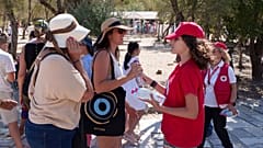 Εθελόντρια του Ερυθρού Σταυρού προσφέρει νερό σε τουρίστες