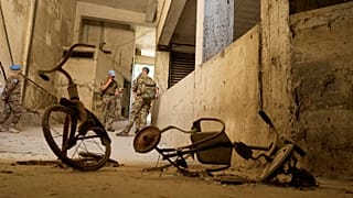 Peacekeepers stand behind two kids’ bicycles inside of an abandoned building inside the UN controlled buffer zone in the central of the divided capital Nicosia, 6 June 2024