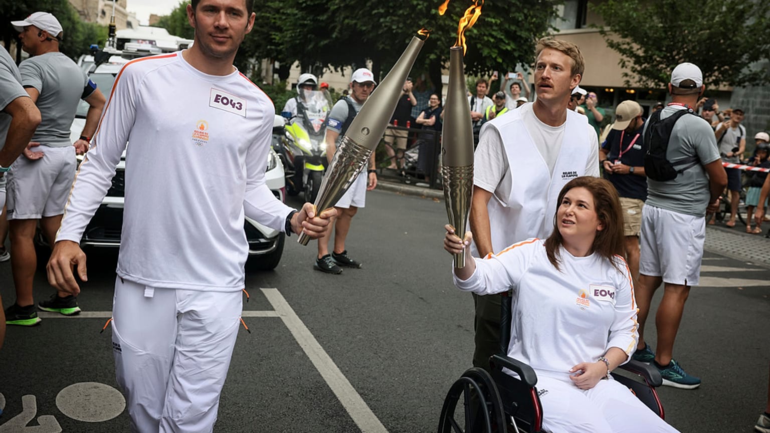 La photographe libanaise Christina Assi, aidée par le journaliste vidéo Dylan Collins, salue après avoir reçu la flamme olympique lors du relais de la flamme olympique