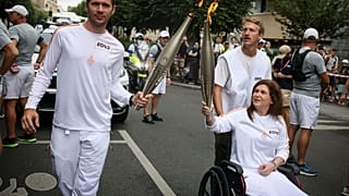 La photographe libanaise Christina Assi, aidée par le journaliste vidéo Dylan Collins, salue après avoir reçu la flamme olympique lors du relais de la flamme olympique