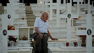 لوكاس ألكسندرو، 94 عامًا، يجلس بجوار قبر ابنه كريستاكيس الذي قُتل أثناء الغزو التركي، قبرص، الجمعة 19 يوليو 2024. 