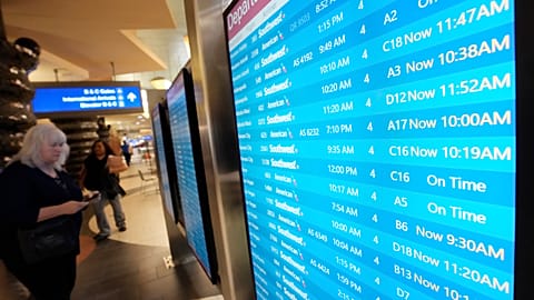 Passengers check a departures board at Phoenix Sky Harbor International Airport Friday, July 19, 2024, in Phoenix.