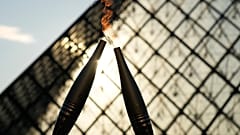 La torche olympique est vue lors d'un relais dans la cour du musée du Louvre dimanche 14 juillet 2024 à Paris.