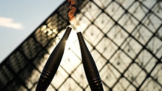 The Olympic torch is seen during a relay in the courtyard of the Louvre Museum Sunday, July 14, 2024 in Paris.