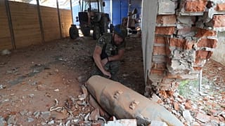 A police officer inspects 250 kilogram (550 pound) unexploded bomb after Russian airstrike on farm warehouse of Bilyi Kolodiaz, Kharkiv region, Ukraine, Thursday, July 11.