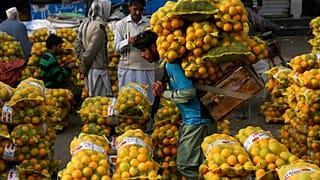  A laborer carries sacks of oranges in a wholesale fruit market in Lahore, Pakistan, on Dec. 1, 2021...