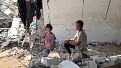 أطفالًا يجلسون بين الأنقاض في طاع غزة، في 5 يوليو 2024.